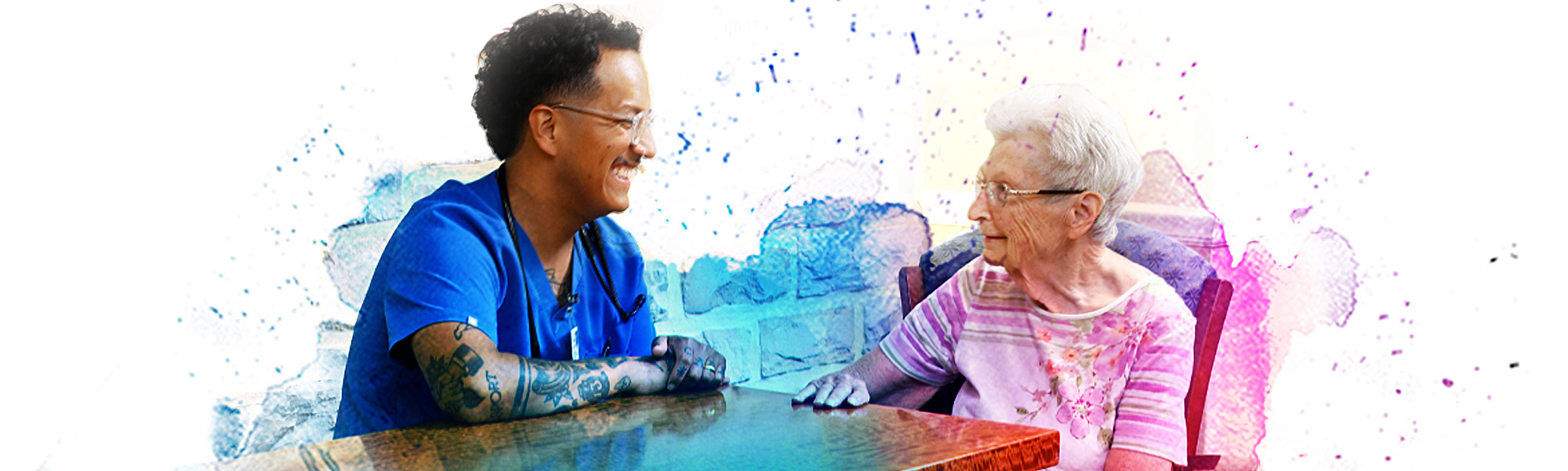 Male nurse seated with a resident sharing a laugh