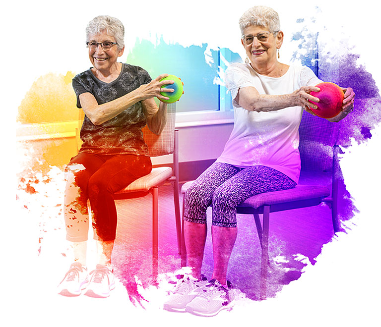 Two females residents participating in a group exercise chair class