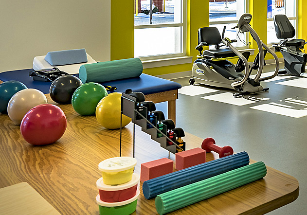 occupational therapy room with table, balls, rollers, and dumbbells