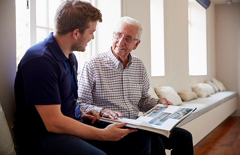Memory support patient looking at scrapbook with the help of a nurse